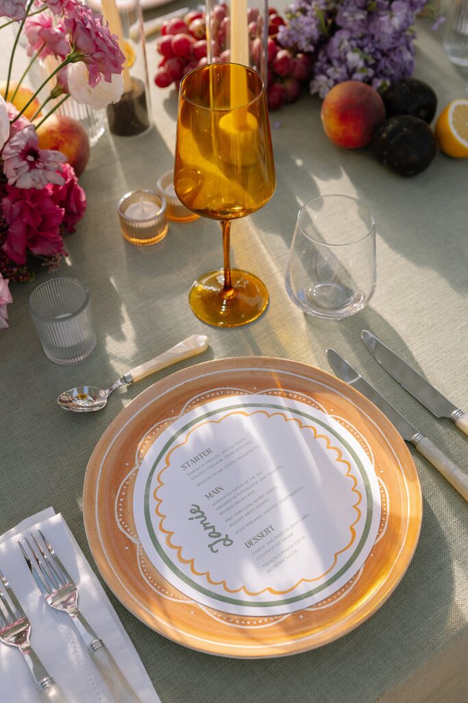 round wedding menus on orange charger with silverware
